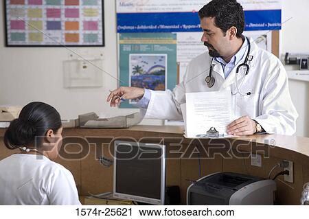 Stock Image - Male doctor standing at a counter. Fotosearch