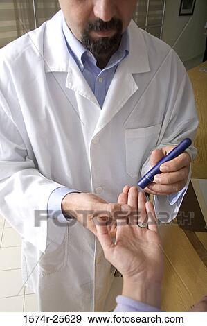 Stock Photo - Male doctor taking a blood sample from a patient's finger. Fotosearch
