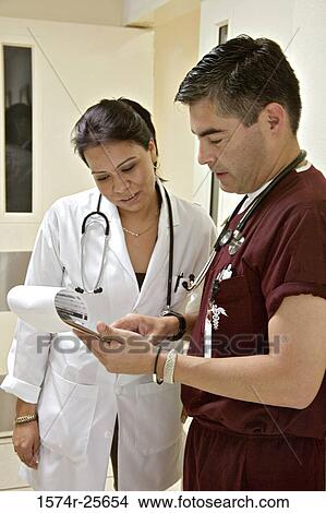Male doctor with a female doctor reading the report of a patient View Large Photo Image Picture - Male doctor with a female doctor reading the report of a patient. Fotosearch
