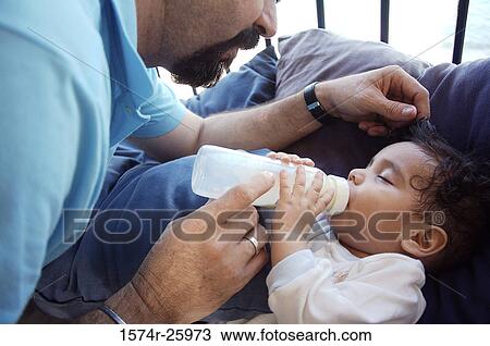 Stock Image - Mature man feeding his baby with a bottle. Fotosearch