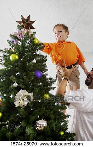 Mature man lifting his son to decorate a Christmas tree View Large Photo Image Stock Image - Mature man lifting his son to decorate a Christmas tree. Fotosearch
