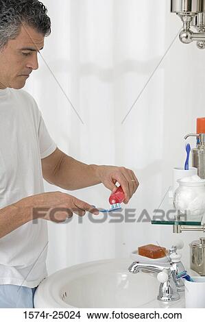 Mature man putting toothpaste on a toothbrush View Large Photo Image Picture - Mature man putting toothpaste on a toothbrush. Fotosearch