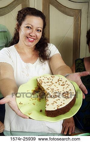 Mature woman showing a cake on a plate and smiling View Large Photo Image Stock Photo - Mature woman showing a cake on a plate and smiling. Fotosearch