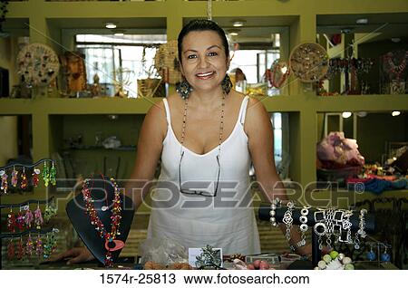 Stock Image - Mature woman standing in a souvenir store and smiling. Fotosearch