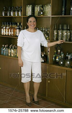 Mature woman standing near a shelf and smiling in a cafe View Large Photo Image Stock Photo - Mature woman standing near a shelf and smiling in a cafe. Fotosearch