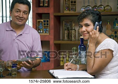 Mature woman talking on a mobile phone and a mature man holding a bottle in a cafe View Large Photo Image Stock Photograph - Mature woman talking on a mobile phone and a mature man holding a bottle in a cafe. Fotosearch