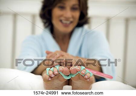 Mature woman wearing toe dividers and holding a nail file View Large Photo Image Stock Image - Mature woman wearing toe dividers and holding a nail file. Fotosearch