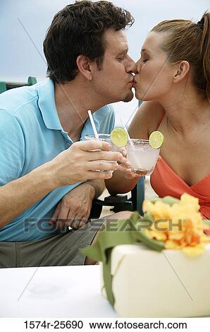 Stock Image - Mid adult man and a young woman kissing each other on the beach. Fotosearch