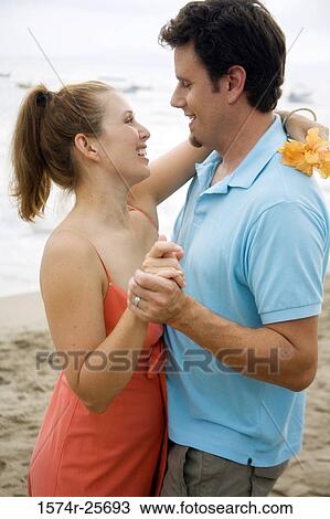 Mid adult man and a young woman looking at each other and smiling on the beach View Large Photo Image Stock Image - Mid adult man and a young woman looking at each other and smiling on the beach. Fotosearch