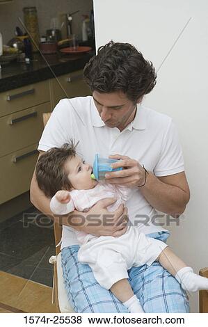 Mid adult man giving his daughter a drinking cup View Large Photo Image Stock Photo - Mid adult man giving his daughter a drinking cup. Fotosearch