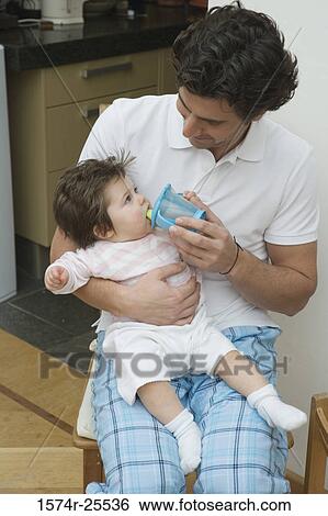 Mid adult man giving his daughter a drinking cup View Large Photo Image Stock Photograph - Mid adult man giving his daughter a drinking cup. Fotosearch