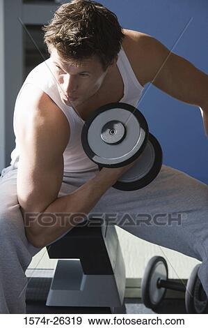 Mid adult man lifting a dumbbell View Large Photo Image Stock Photo - Mid adult man lifting a dumbbell. Fotosearch