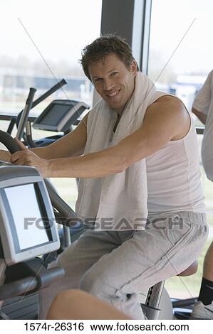 Mid adult man sitting on an exercise machine View Large Photo Image Stock Photograph - Mid adult man sitting on an exercise machine. Fotosearch
