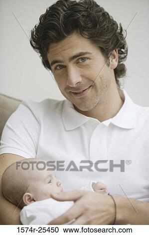 Mid adult man smiling and holding his baby View Large Photo Image Stock Image - Mid adult man smiling and holding his baby. Fotosearch