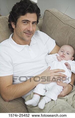 Mid adult man smiling and holding his baby View Large Photo Image Stock Image - Mid adult man smiling and holding his baby. Fotosearch