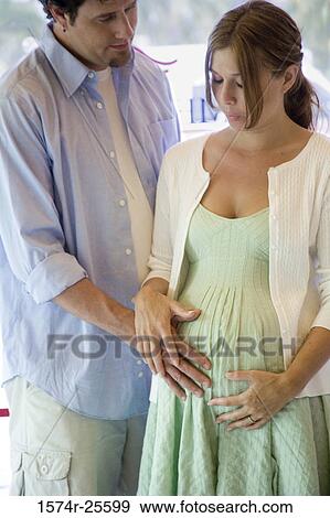 Mid adult man touching the abdomen of a pregnant young woman View Large Photo Image Stock Photo - Mid adult man touching the abdomen of a pregnant young woman. Fotosearch