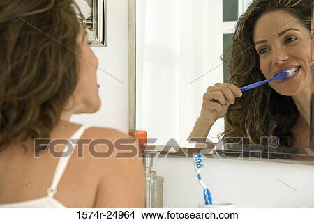 Mid adult woman brushing her teeth View Large Photo Image Picture - Mid adult woman brushing her teeth. Fotosearch