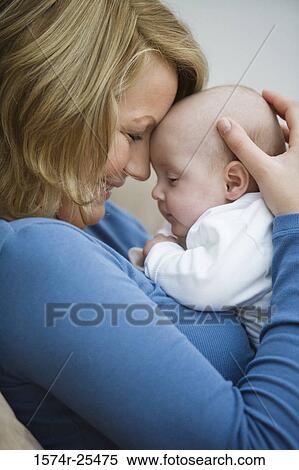 Stock Photography - Mid adult woman cuddling with her baby. Fotosearch