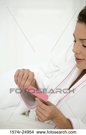 Mid adult woman filing her fingernails View Large Photo Image Picture - Mid adult woman filing her fingernails. Fotosearch