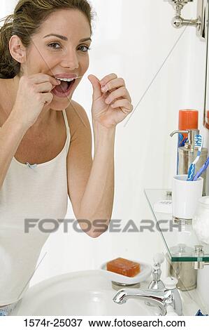 Mid adult woman flossing her teeth and leaning over a sink View Large Photo Image Stock Photo - Mid adult woman flossing her teeth and leaning over a sink. Fotosearch
