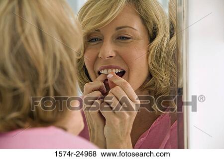 Mid adult woman flossing her teeth View Large Photo Image Stock Photo - Mid adult woman flossing her teeth. Fotosearch