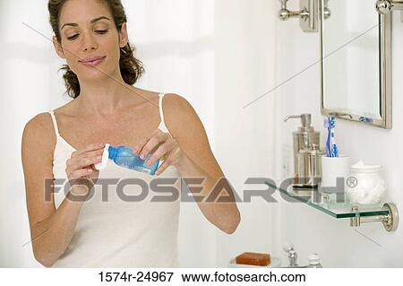 Mid adult woman holding a bottle and a cotton pad View Large Photo Image Stock Photo - Mid adult woman holding a bottle and a cotton pad. Fotosearch
