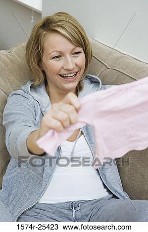 Mid adult woman holding baby clothing View Large Photo Image Stock Image - Mid adult woman holding baby clothing. Fotosearch