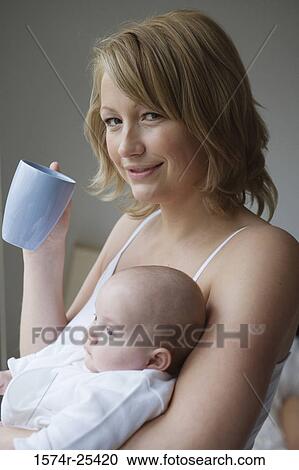 Mid adult woman holding her baby and a coffee cup View Large Photo Image Stock Image - Mid adult woman holding her baby and a coffee cup. Fotosearch
