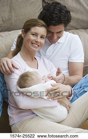 Mid adult woman holding her baby with a mid adult man sitting beside her View Large Photo Image Stock Image - Mid adult woman holding her baby with a mid adult man sitting beside her. Fotosearch