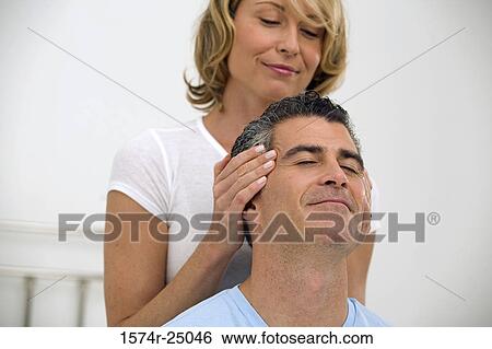 Mid adult woman massaging the temples of a mature man View Large Photo Image Stock Photograph - Mid adult woman massaging the temples of a mature man. Fotosearch