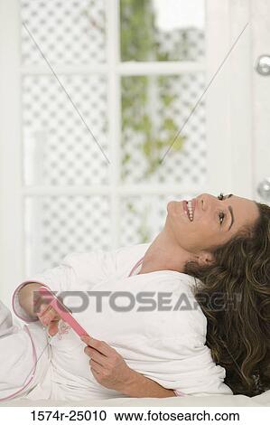Mid adult woman reclining on the bed and filing her fingernails View Large Photo Image Stock Image - Mid adult woman reclining on the bed and filing her fingernails. Fotosearch