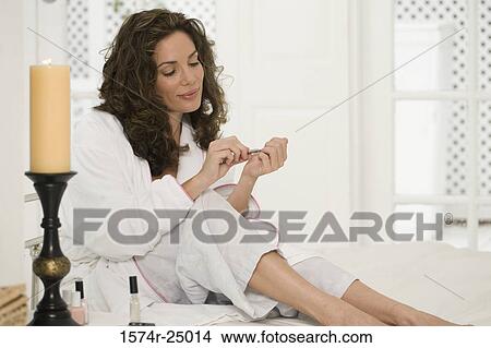 Mid adult woman sitting and cutting her fingernails View Large Photo Image Picture - Mid adult woman sitting and cutting her fingernails. Fotosearch