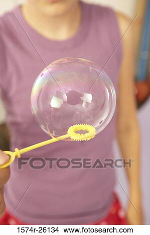 Mid section view of a girl holding a bubble on a bubble wand View Large Photo Image Picture - Mid section view of a girl holding a bubble on a bubble wand. Fotosearch