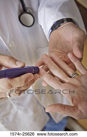 Stock Photograph - Mid section view of a male doctor taking a blood sample from a patient's finger. Fotosearch