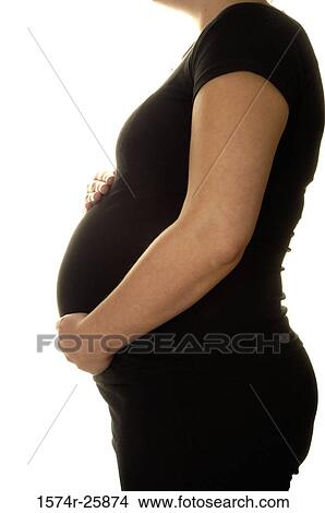 Mid section view of a pregnant woman touching her abdomen View Large Photo Image Picture - Mid section view of a pregnant woman touching her abdomen. Fotosearch