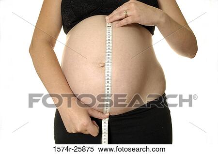 Stock Photography - Mid section view of a pregnant woman measuring her abdomen. Fotosearch