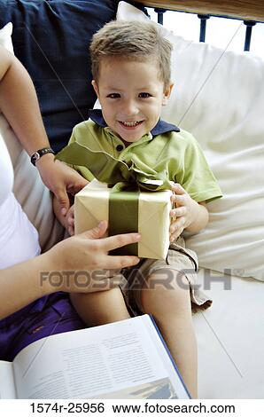 Mid section view of a woman giving a gift to her son sitting on her lap View Large Photo Image Stock Photograph - Mid section view of a woman giving a gift to her son sitting on her lap. Fotosearch