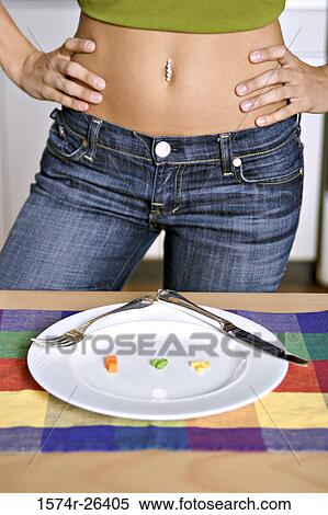 Mid section view of a young woman standing with arms akimbo at the dining table View Large Photo Image Stock Photography - Mid section view of a young woman standing with arms akimbo at the dining table. Fotosearch