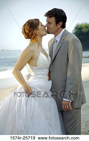 Stock Photo - Newlywed couple kissing each other on the beach. Fotosearch