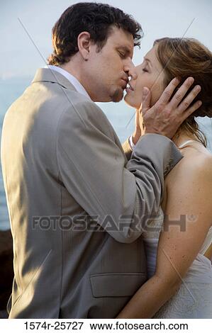 Stock Photo - Newlywed couple kissing each other. Fotosearch