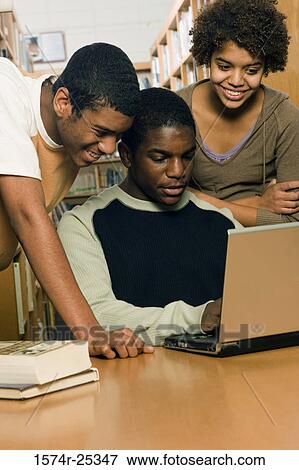One student using a laptop with two students watching him View Large Photo Image Stock Photo - One student using a laptop with two students watching him. Fotosearch