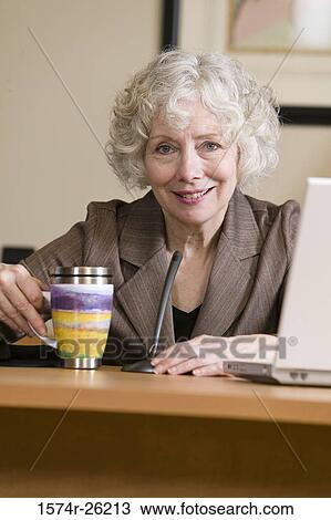 Portrait of a businesswoman sitting at a desk View Large Photo Image Stock Image - Portrait of a businesswoman sitting at a desk. Fotosearch