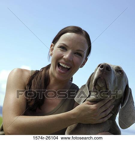 Portrait of a mid adult woman holding her dog and laughing View Large Photo Image Picture - Portrait of a mid adult woman holding her dog and laughing. Fotosearch