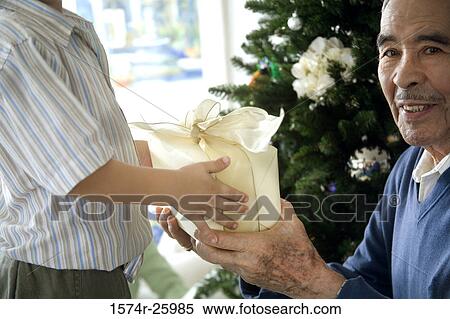 Stock Photography - Portrait of a senior man giving a gift to his great-grandson and smiling. Fotosearch