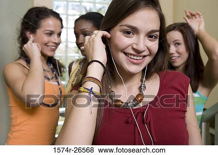Portrait of a teenage girl listening to music with her friends in the background View Large Photo Image Stock Photo - Portrait of a teenage girl listening to music with her friends in the background. Fotosearch
