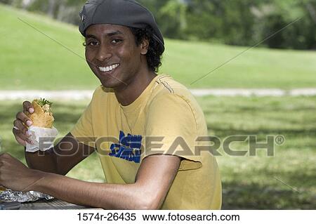 Portrait of a young man eating a sandwich View Large Photo Image Stock Photography - Portrait of a young man eating a sandwich. Fotosearch
