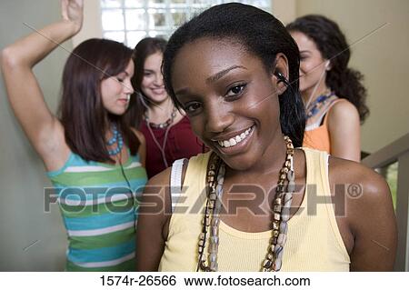 Portrait of a young woman smiling with her friends in the background View Large Photo Image Stock Photograph - Portrait of a young woman smiling with her friends in the background. Fotosearch