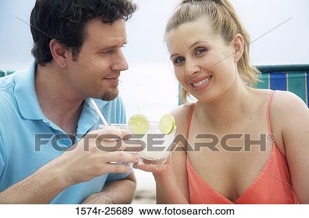 Portrait of a young woman with a mid adult man toasting on the beach View Large Photo Image Stock Photo - Portrait of a young woman with a mid adult man toasting on the beach. Fotosearch
