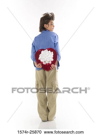 Rear view of a boy holding a heart shape valentine behind his back View Large Photo Image Stock Image - Rear view of a boy holding a heart shape valentine behind his back. Fotosearch