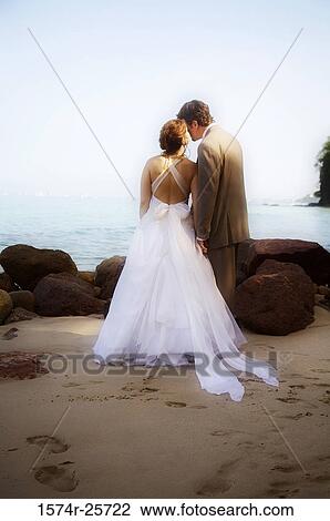 Rear view of a bride kissing her groom on the beach View Large Photo Image Stock Image - Rear view of a bride kissing her groom on the beach. Fotosearch